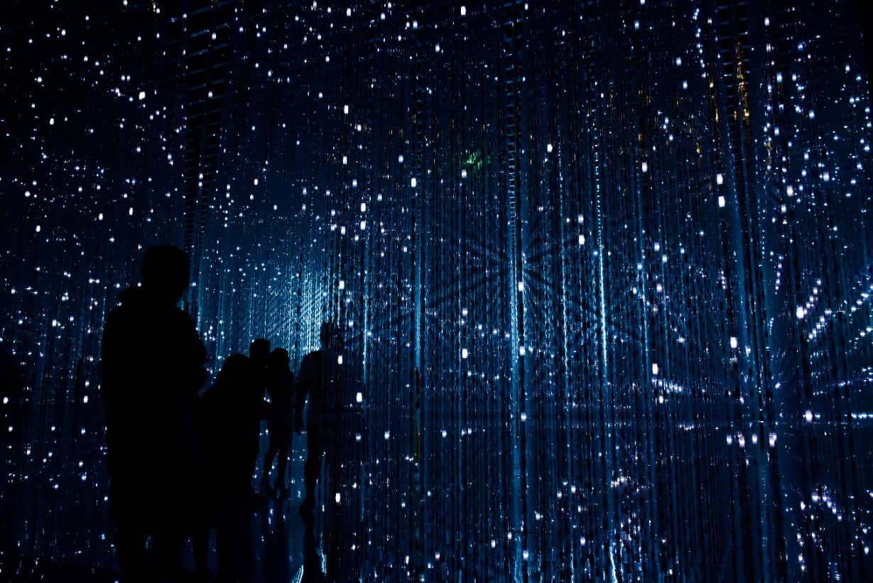 People stand among bright lights that mimic a futuristic matrix.